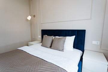 The bedroom is stylishly decorated with a bed covered in white sheets, pillows, and a blue...