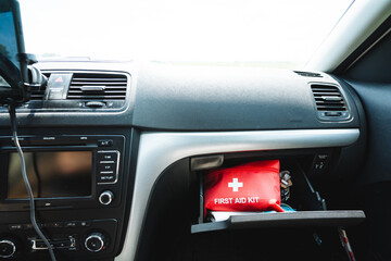 A red car first aid kit is in the glove compartment of the car, the interior of the car from the inside, the dashboard.