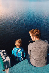 Fototapeta premium Above, child and father at lake for fishing, summer and vacation together in sunshine teaching. Family, fisherman and boy in nature by water for holiday, learning and outdoor adventure with dad
