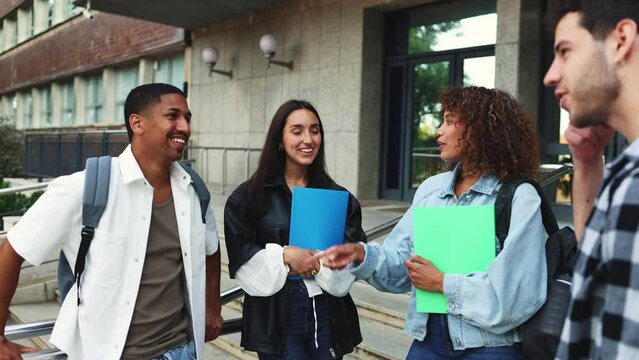 Multicultural students socializing happily at contemporary campus. Diverse students socializing outside a modern university, capturing a positive and inclusive campus environment