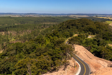 View of an empty paved rural road, flanked by Atlantic forest and eucalyptus fields in a mountain range in Brazil