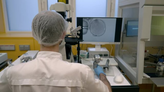 Doctor operating the modern ivf equipment for sperm injection into the female egg. Ivf machine slowly injecting the sperm into the ovary. Ivf inspection screen displays the artificial sperm injection.