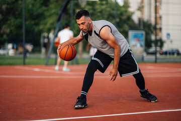 Naklejka premium Man in motion playing basketball n an outdoor court