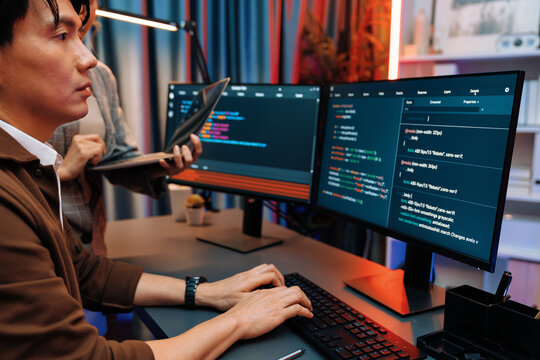 Serious of IT developers discussing intelligent website development coder system running data online two screens with laptop showing information network at neon light room at modern office. Infobahn.