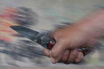 The image shows the fist of a man wielding a knife. Knife attacks are dramatically increasing in...