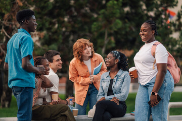 Happy diverse students standing at campus and chatting on coffee break