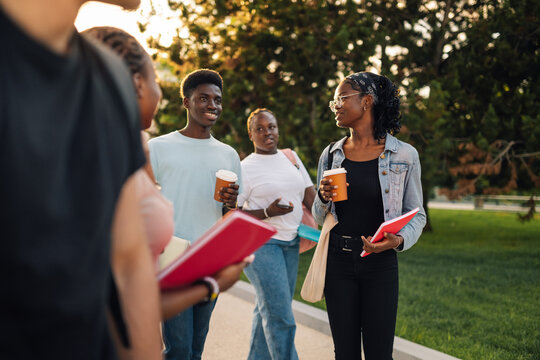 Happy diverse college students walking at university campus with coffee
