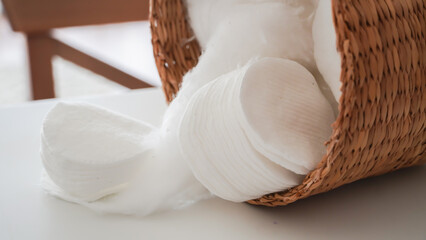 Make-up remover cotton and cotton balls in a wicker basket on background