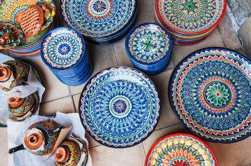 traditional colorful Uzbek plates and ceramic dishes hand-painted at the street oriental bazaar in...