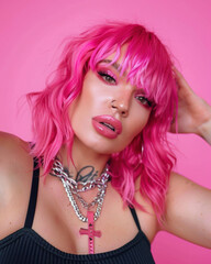 Naklejka premium Transgender woman bright pink hair, posing confidently against soft pink studio background
