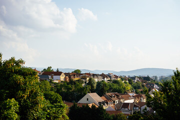 Fototapeta premium Orange brown tiled roof of the houses with solar panels. Traditional street. Amazing landscape with mountains and houses of Eger. Different size and colors building in Europe. Lifestyle of Hungary.