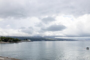 coastal landscape with a cloudy sky and calm waters, featuring a distant shoreline and a small boat