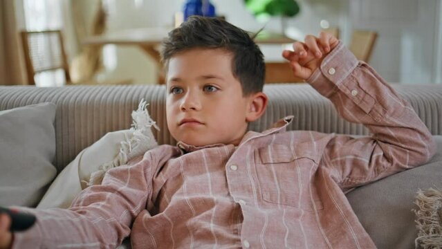 Lazy boy holding controller switching channels sofa closeup. Bored kid resting