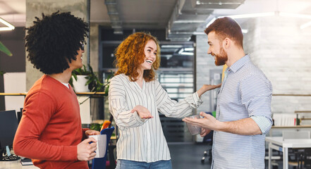 Very friendly girl hugging young man, welcoming new member of creative team in modern office