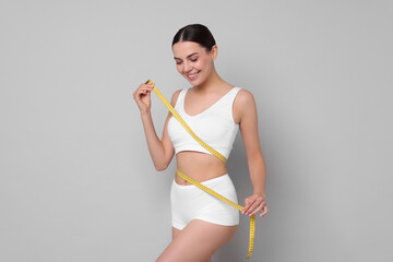 Diet and weight loss concept. Beautiful young woman with measuring tape showing her slim body...