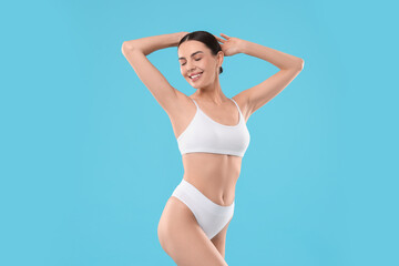 Diet and weight loss concept. Beautiful young woman with slim body against light blue background