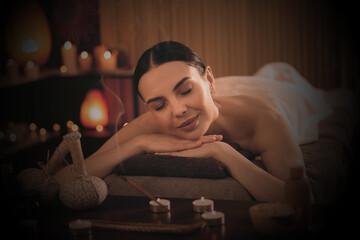 Beautiful young woman lying on massage table in salon