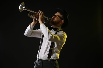 Professional musician playing trumpet on black background in color lights