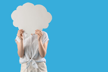 Young woman hiding face behind blank speech bubble on blue background