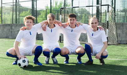 Junior football players sitting together on field with ball