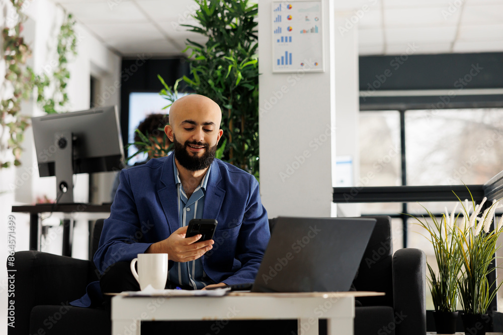Poster smiling start up business employee chatting on smartphone while having work break in open space offi