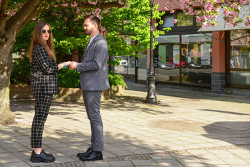 Beautiful loving young couple holding hands near blooming tree on sunny spring day