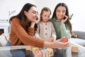 Young lesbian couple and adopted little girl playing with cubes at home