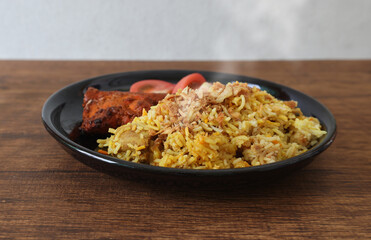 木製テーブルに置かれた黒い皿にもったビリヤニ