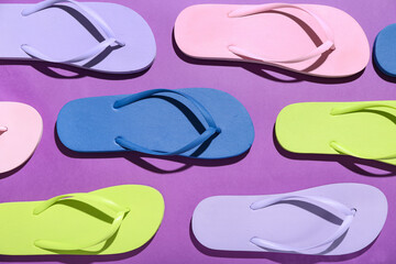 Colorful pairs of flip flops on purple background