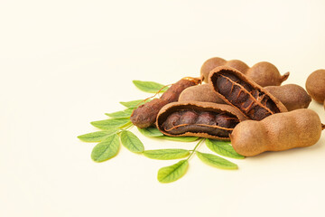 Heap of tasty tamarinds and leaves on yellow background