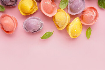 Colorful raw dumplings with basil on pink background