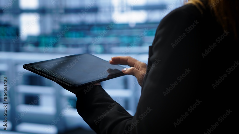 Poster system administrator monitoring server room, doing checkup, inputting data on tablet of needed fixes