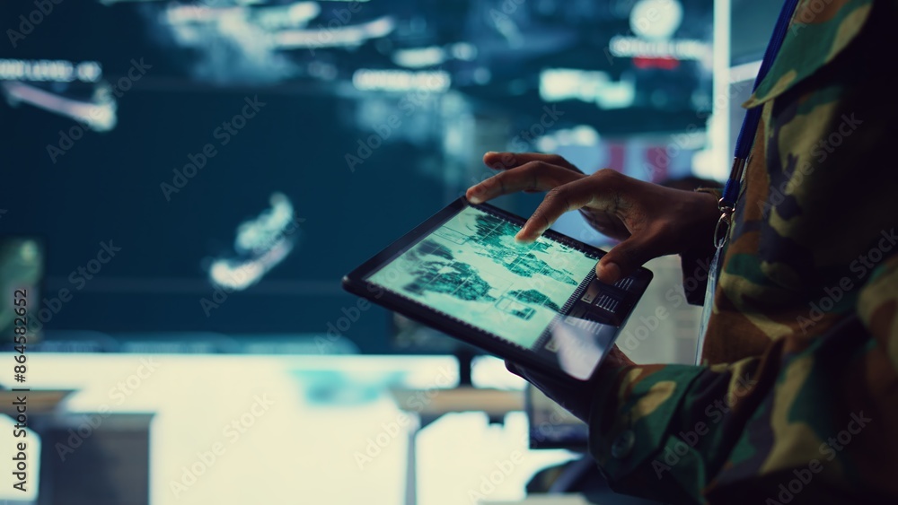Poster army soldier reviews targets on a satellite world map to ensure global protection, works on tablet i
