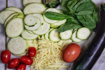Plate with vegetables, whole and sliced zucchini, spinach, tomatoes, cheese and egg