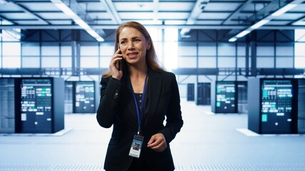Software engineer talking on smartphone in data center, coordinating server maintenance tasks....