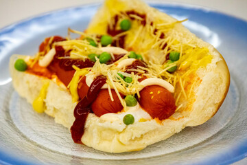 Traditional Brazilian style hot dog with sausage, peas and straw potatoes