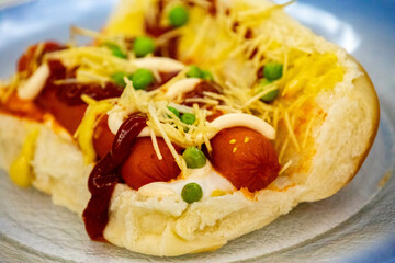 Traditional Brazilian style hot dog with sausage, peas and straw potatoes
