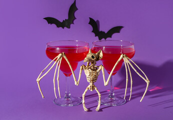 Bat skeleton with glasses of tasty cocktail for Halloween celebration on purple background