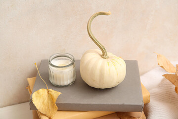 Burning candle with autumn leaves, pumpkin and books on white background
