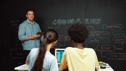 Caucasian teacher answering student question while holding tablet. Caucasian girl pointing at...