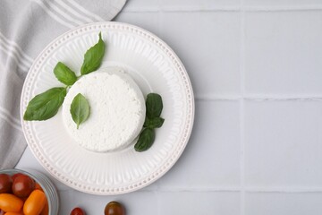 Fresh ricotta (cream cheese), basil and tomatoes on light tiled table, flat lay. Space for text