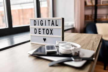 technology concept - digital detox words on light box and different gadgets on blue background