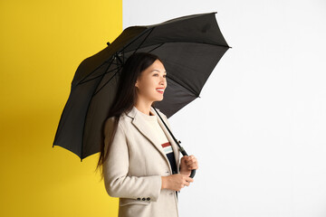 Beautiful young Asian woman with umbrella on color background