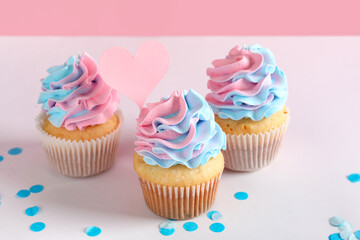 Delicious cupcakes with confetti on table against pink background. Gender reveal party concept