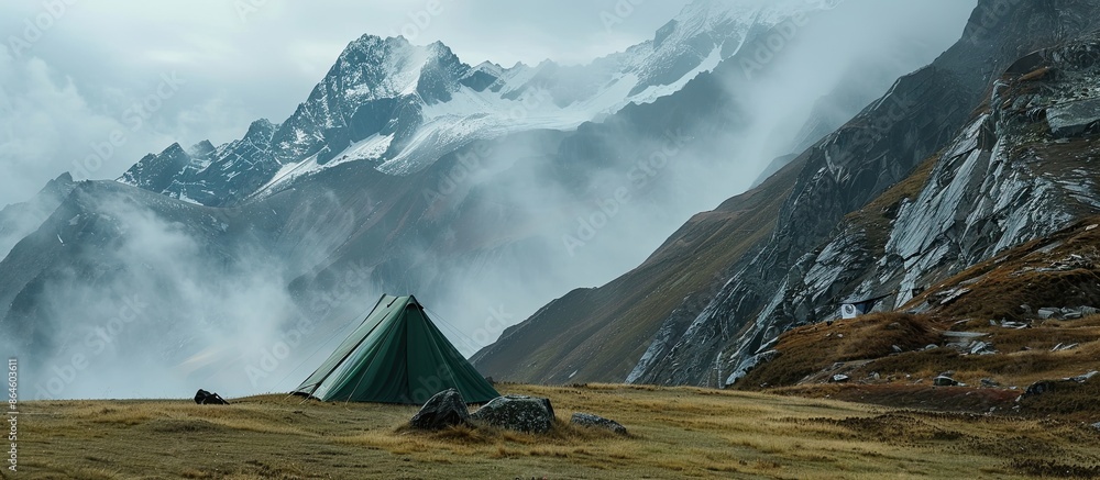 Poster a green camping tent set against mist-covered mountain peaks, providing copy space for adding text o