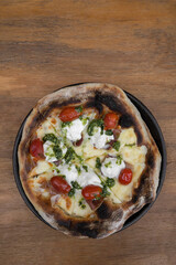 Pizza background. Closeup view of a pizza with mozzarella and burrata cheese, cherry tomatoes and prosciutto.