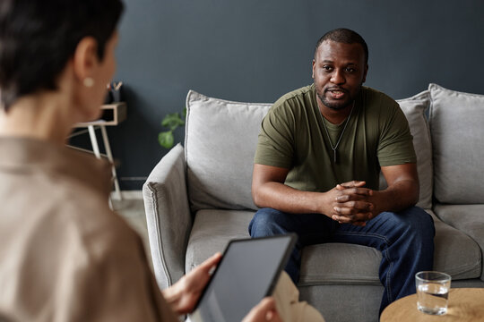 Portrait of African American adult man as army veteran sharing struggles with mental health therapist in session - Powered by Adobe