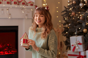 Young woman in reindeer horns with Advent calendar at home on Christmas eve