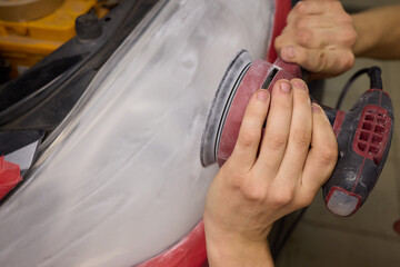 Person using a machine to polish automotive lighting on a car headlight