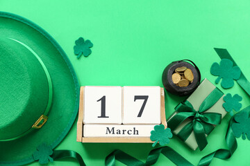 Pot with golden coins, leprechaun hat and calendar on green background. St. Patrick's Day...